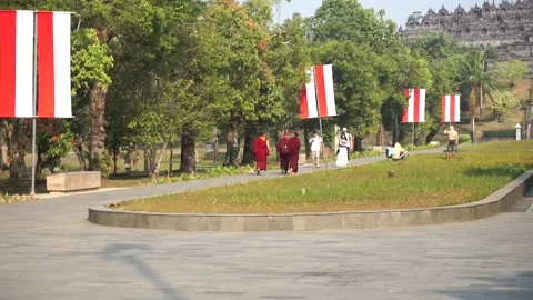 Several monks in maroon robes walk along the pedestrian pathway in the Borobudur Stock-Footage 341676076