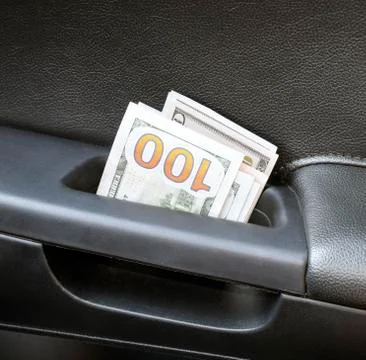 Several notes of US dollars and are folded in half in the door handle of th.. Photos