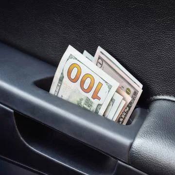 Several notes of US dollars and are folded in half in the door handle of the  Photos