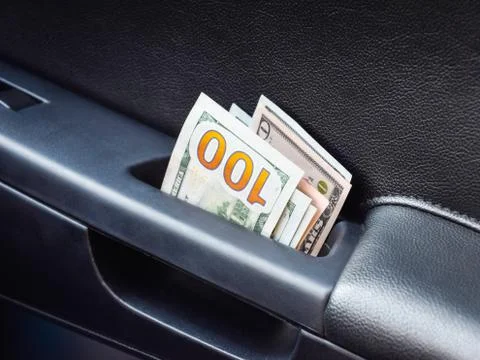 Several notes of US dollars and are folded in half in the door handle of the  Photos