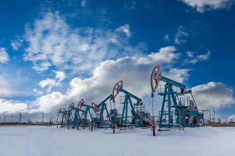 Several Oil pumpjack under the blue sky with clouds winter working. Oil rig e Stock Photos