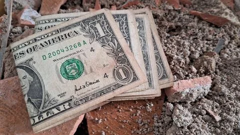 Several old one dollar bills resting on broken red brick rubble Stock Photos