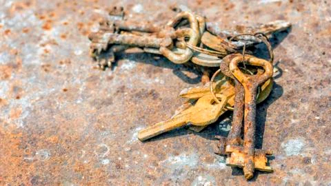 Several old rusty keys on ring shot on steel textured background Stock Photos