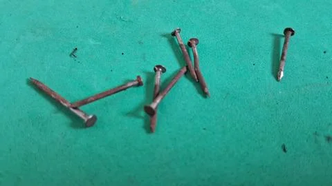 Several old rusty metal nails scattered on a bright green surface Stock Photos