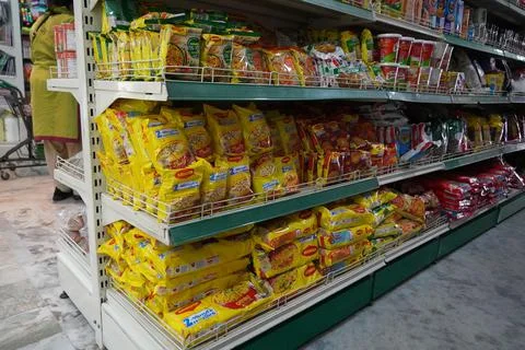 Several packets of packaged noodles kept on shelf for sale. Maggi instant noo Stock Photos