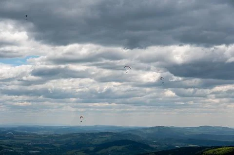 Several paragliders soaring in the sky with dramatic clouds in the backgrou.. Stock Photos