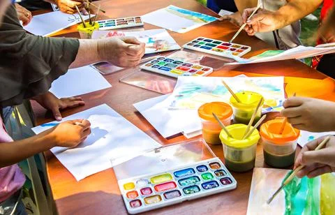 Several of people draw on paper using watercolor paints sitting at the same t Stock-Fotos
