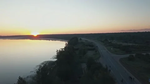 Several people walk along an empty road along the river and woods at dawn on an Stock Footage 172359134