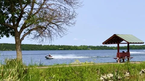 Several personal water craft speeding by the shore of a Minnesota lake Stock Footage 251923742