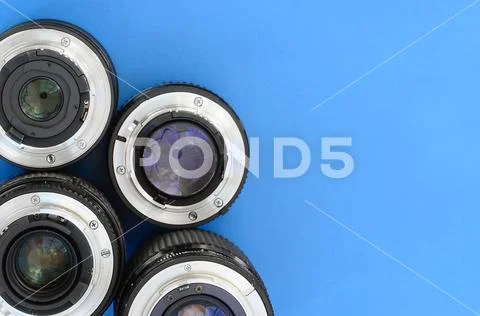 Several photographic lenses lie on a bright blue background. Space for text Stock Photos