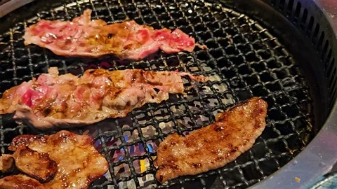 Several pieces of beef are grilled over a charcoal fire. Stock Footage 238760997