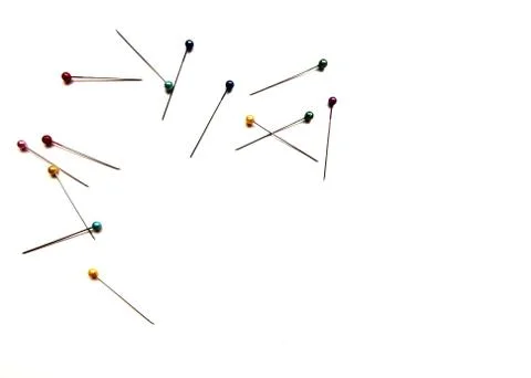 Several pins for sewing with colored beads lie on a white isolated background Stock Photos