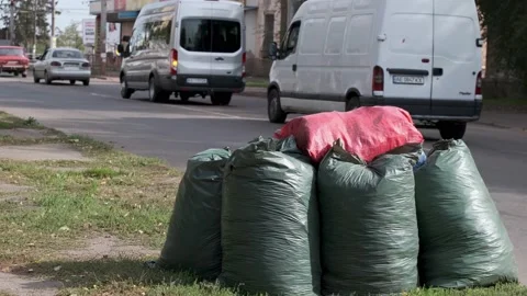 Several plastic bags filled with garbage on city street. Cars go along the road. Stock Footage 140740105