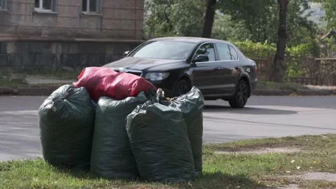 Several plastic bags filled with garbage on city street. Cars go along the road. Stock Footage 140740243