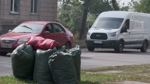 Several plastic bags filled with garbage on city street. Cars go along the road. Stock Footage 141333318