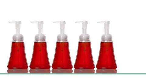 Several plastic hand soap bottles on a glass shelf Stock Photos