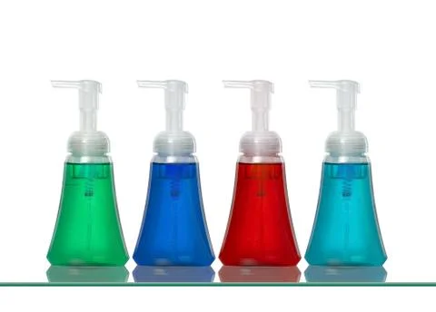Several plastic hand soap bottles on a glass shelf Stock Photos
