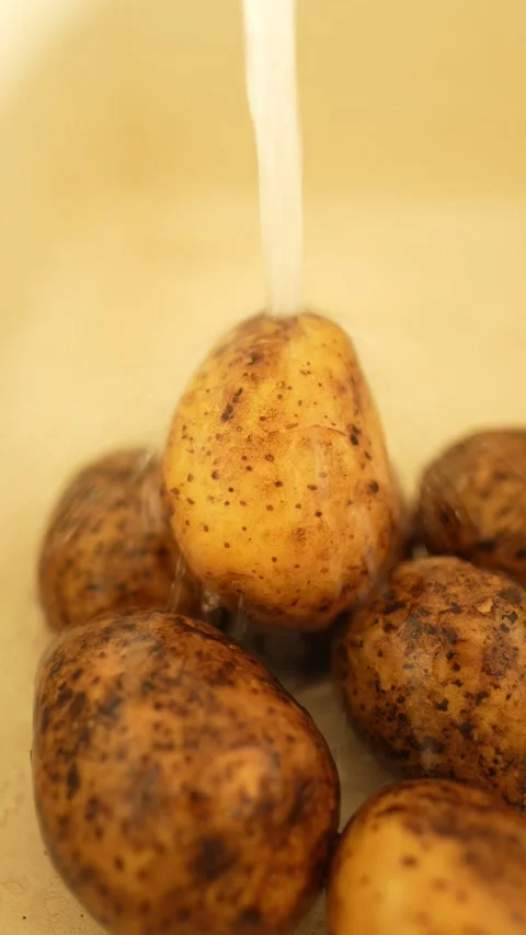 Several potatoes under running water in the sink Stock Footage 327773870