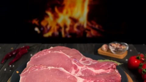 Several raw pork steaks, composition on a wooden board with spices. Stock Footage 154631404