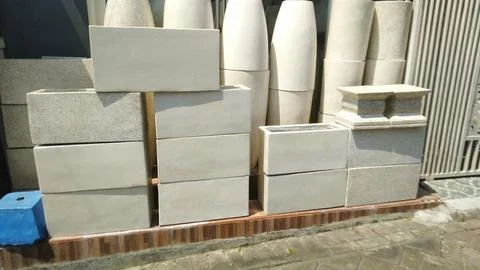 Several rectangular concrete planters and tall vases are displayed outdoors Stock Photos