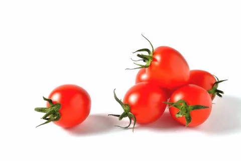 Several red cherry tomatoes with green leaves and one lying separately on a w Stock Photos