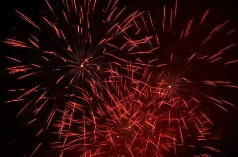 Several red colored firework explosions in open night sky Foto stock