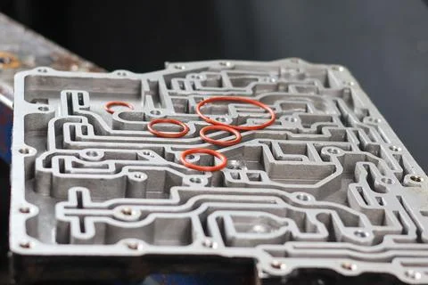 Several red O-rings resting on an automatic transmission valve body. Stock Photos