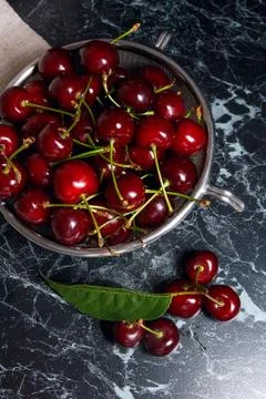 Several red sweet cherries and big green leaf on the table. Fresh organic che Stock Photos