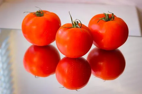 Several red tomatoes on a mirror surface Stock Photos