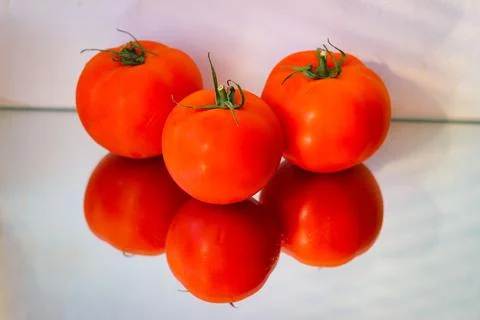 Several red tomatoes on a mirror surface Foto stock
