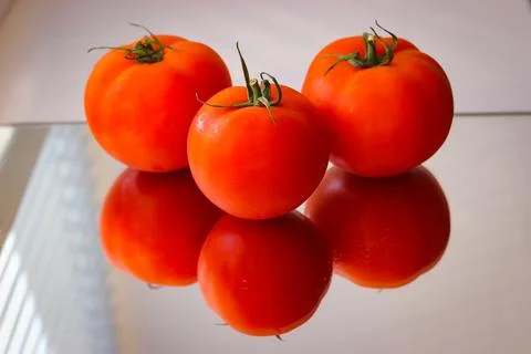 Several red tomatoes on a mirror surface Foto stock