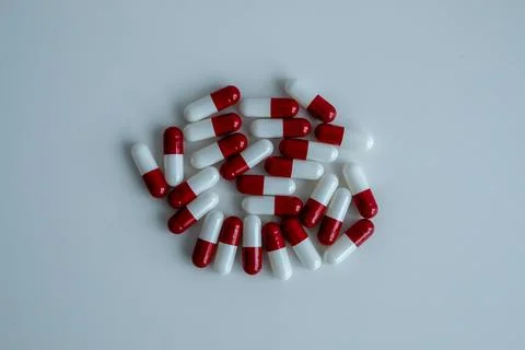 Several red-white capsules were scattered with a white background. Stock Photos
