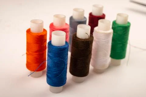 Several reels of multicolored sewing thread on a white background. Close up. Stock Photos