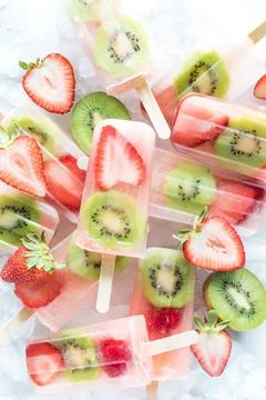 Several refreshing strawberry kiwi popsicles in a pile on ice. Stock Photos