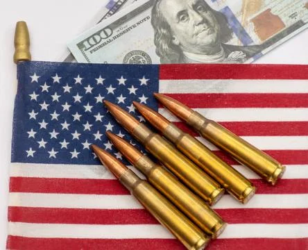 Several rifle bullets placed on a small United States flag with hundred dolla Stock Photos