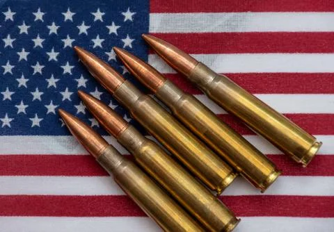 Several rifle bullets placed on a small United States flag with hundred dolla Stock Photos