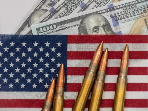 Several rifle bullets placed on a small United States flag with hundred dolla Stock Photos