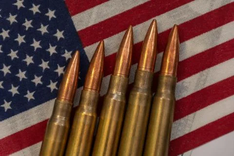 Several rifle bullets placed on a small United States flag with hundred dolla Foto stock