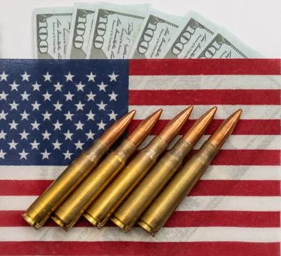 Several rifle bullets placed on a small United States flag with hundred dolla Stock Photos