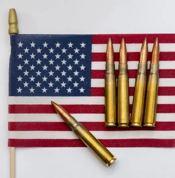 Several rifle bullets placed on a small United States flag with hundred dolla Stock Photos