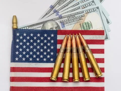 Several rifle bullets placed on a small United States flag with hundred dolla Stock Photos