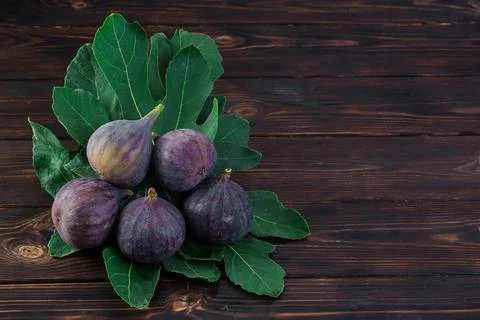 Several ripe figs on fig tree leaves on an old wooden table, horizontal fra.. Stock Photos