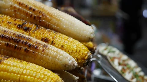 Several roasted corn cobs arranged on a metal grill at a street vendor counter Stockbeeldmateriaal 333046517