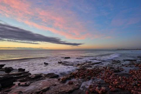 Several rocks on the beach in the warm light of a sunrise Stock Photos