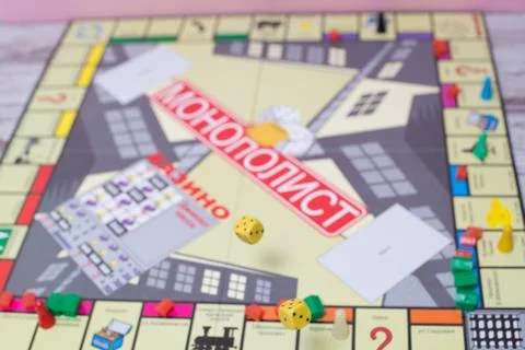 Several rolling red dice fall on table with boardgame. Gameplay moments Stock Photos