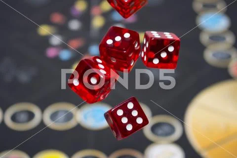 Several rolling red dice fall on a table with boardgame. Gameplay moments Stock Photos