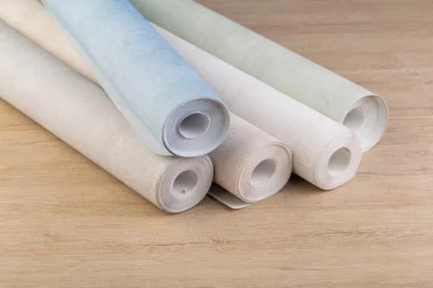 Several rolls of multi-colored paper wallpaper on a wooden table Stock Photos