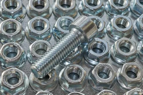 Several rows of hex nuts with round base and top threaded bolt. Stock Photos