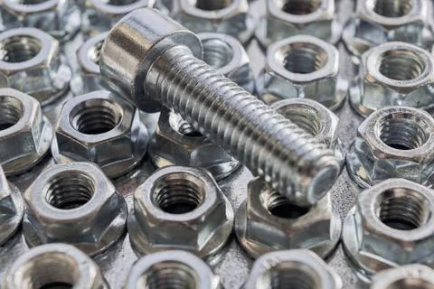 Several rows of hex nuts round base and on top is a threaded bolt. Stock-Fotos