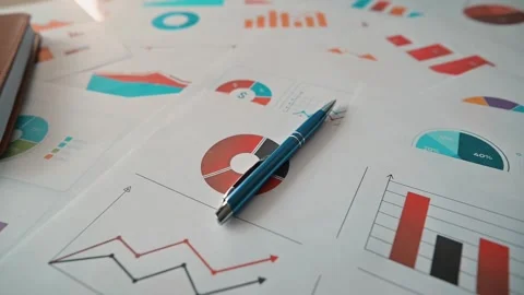 Several sheets of paper with colorful graphs and charts are spread across a 库存影片 338302490